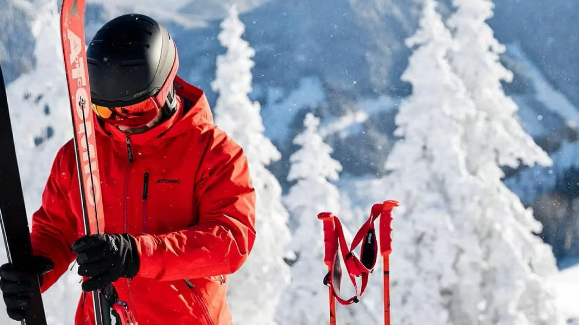 Skifahrer in roter Jacke auf verschneitem Berg