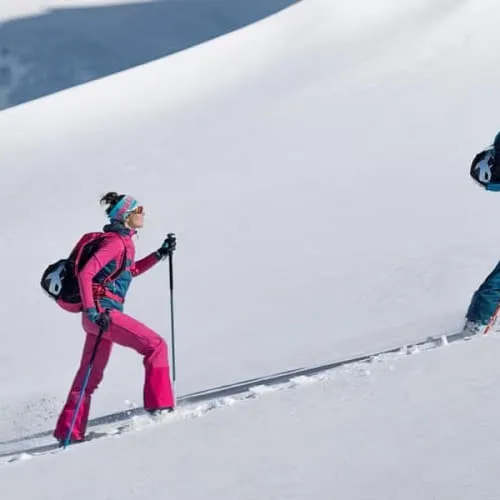 Drei Skifahrer steigen einen schneebedeckten Hang hoch
