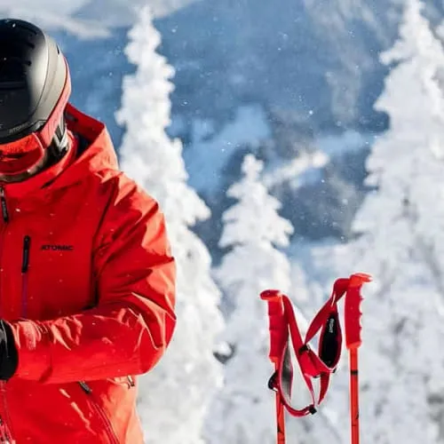 Skifahrer in roter Jacke vor schneebedeckten Bergen